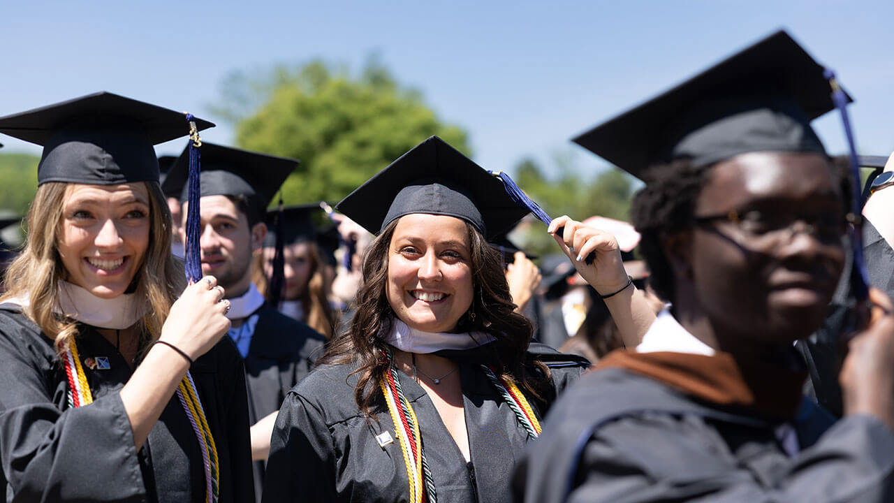 graduates smiling while they move their tassels from the right to the left