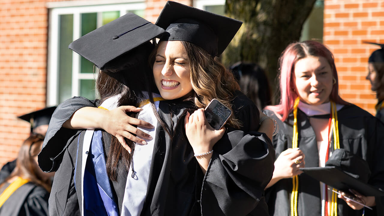 Students embrace in front of School of Communications