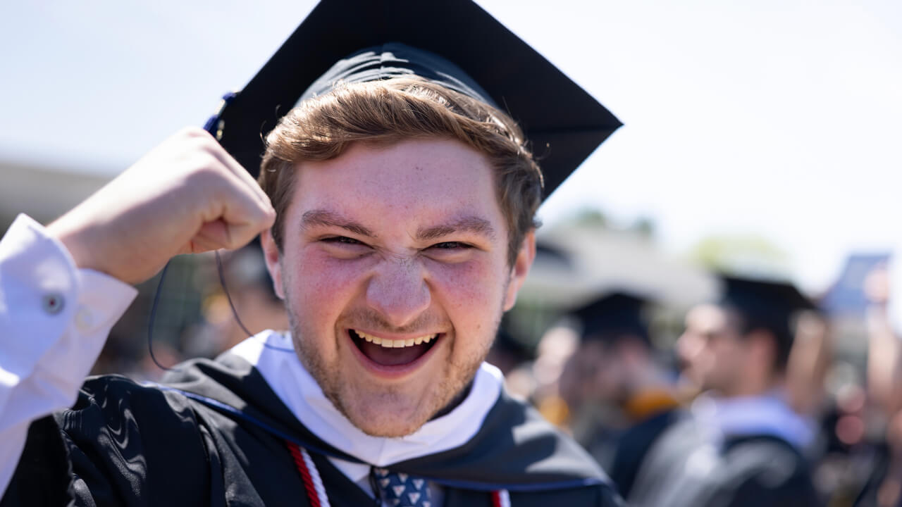 A graduate pumps his fist in celebration and cheers