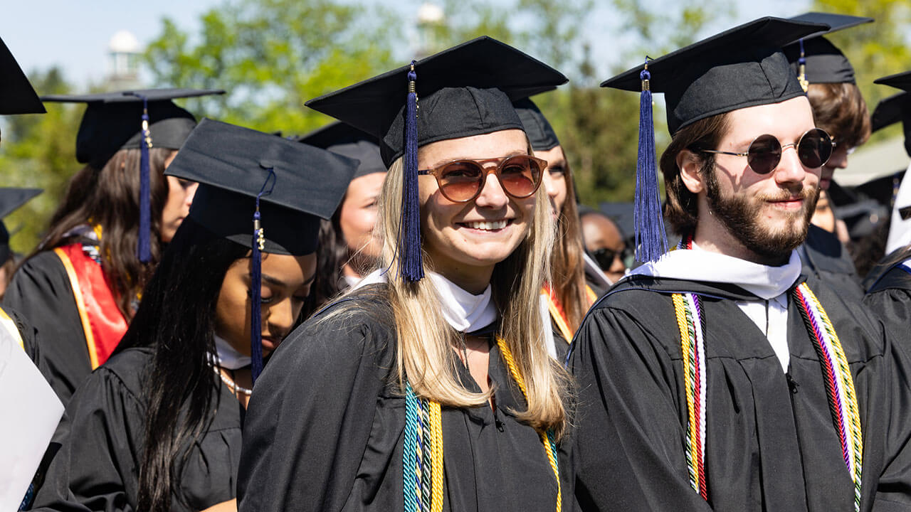 graduates smile widely as the notice the camera pointed at their line