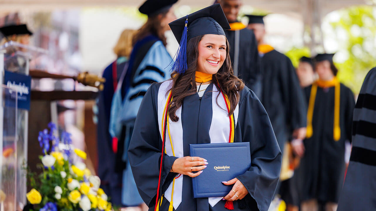 Student smiles with her diploma in hand