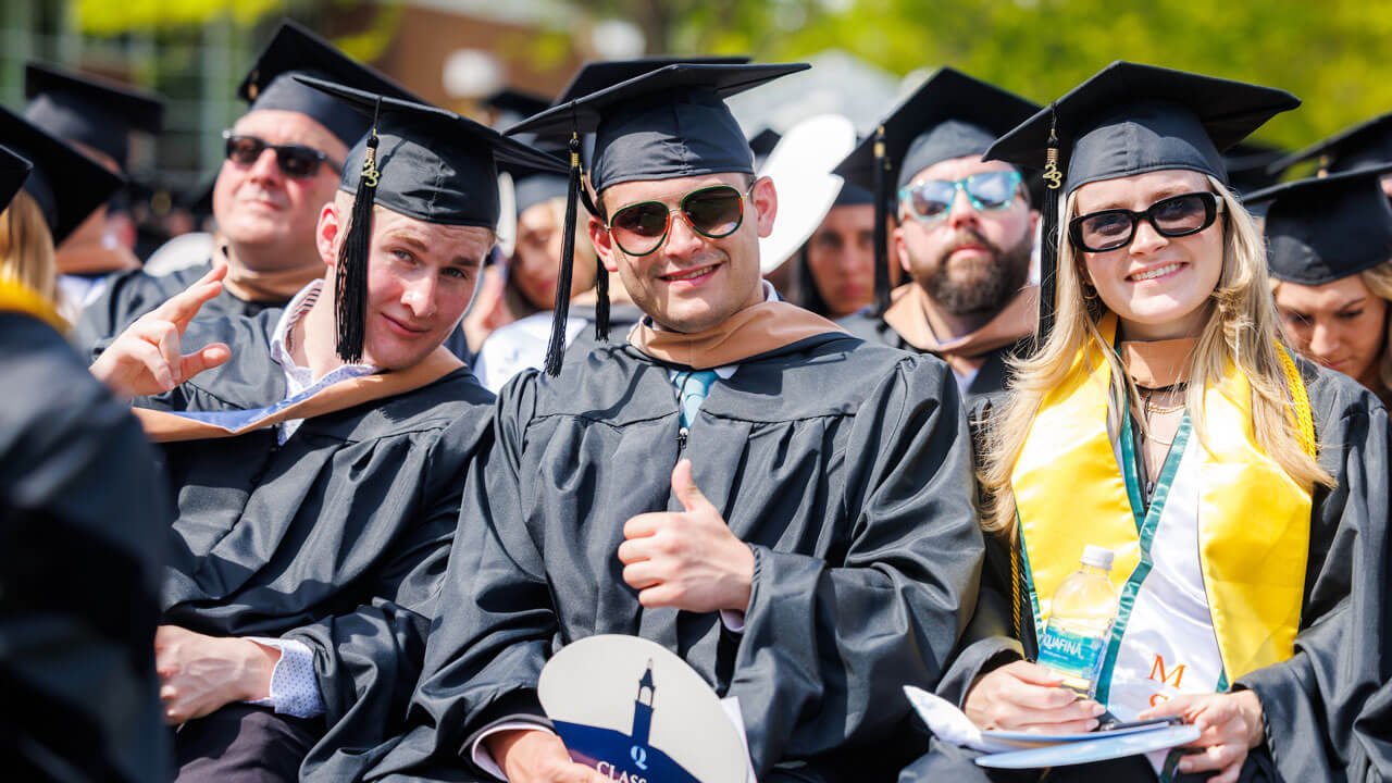 Graduates sitting in seats and giving photographer thumbs up