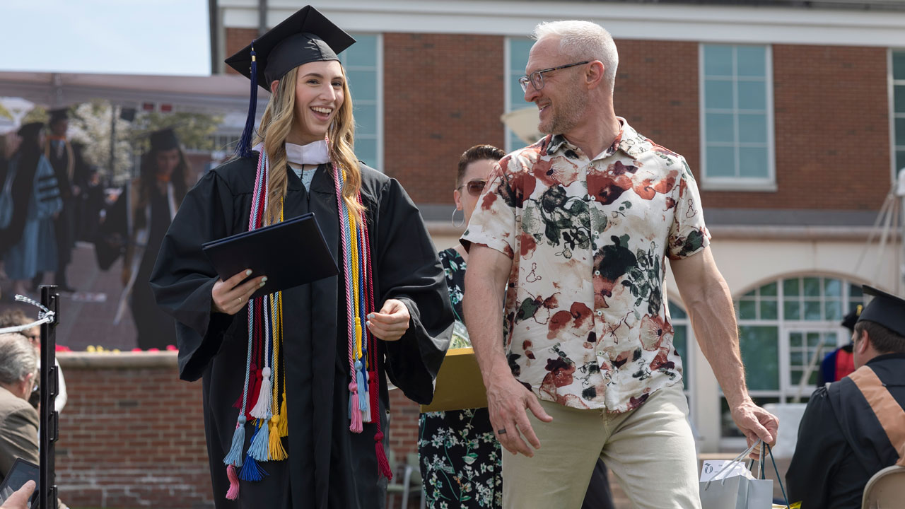 SOB Graduate walks and smiles with parent