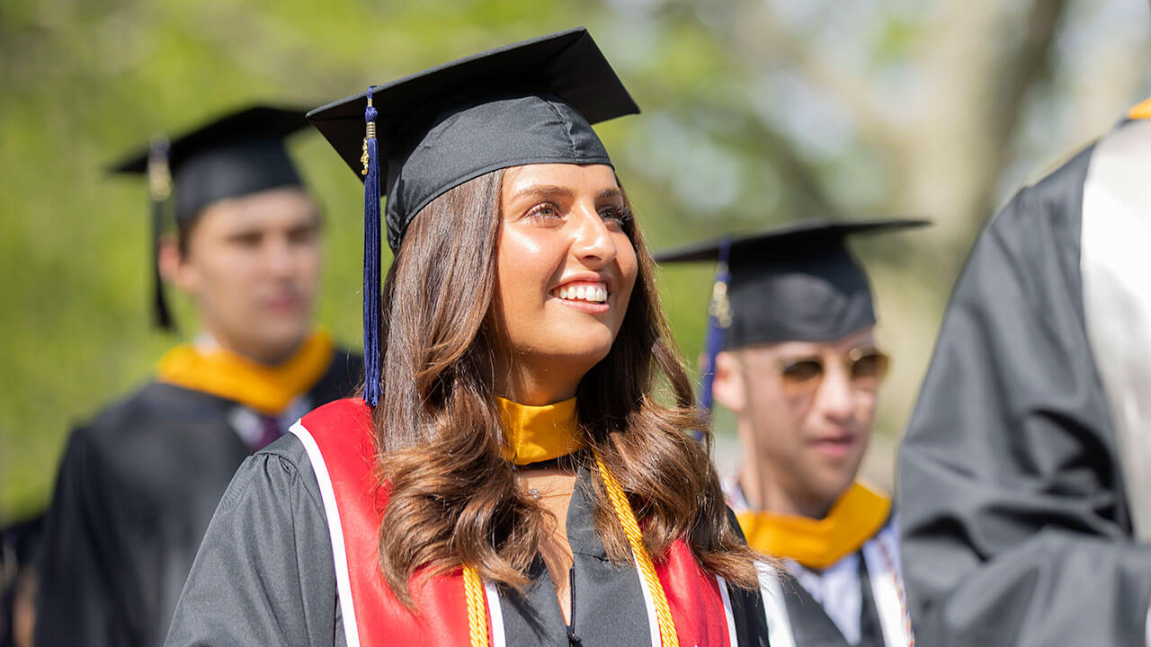 Business student smiling up at the stage in her cap and gown