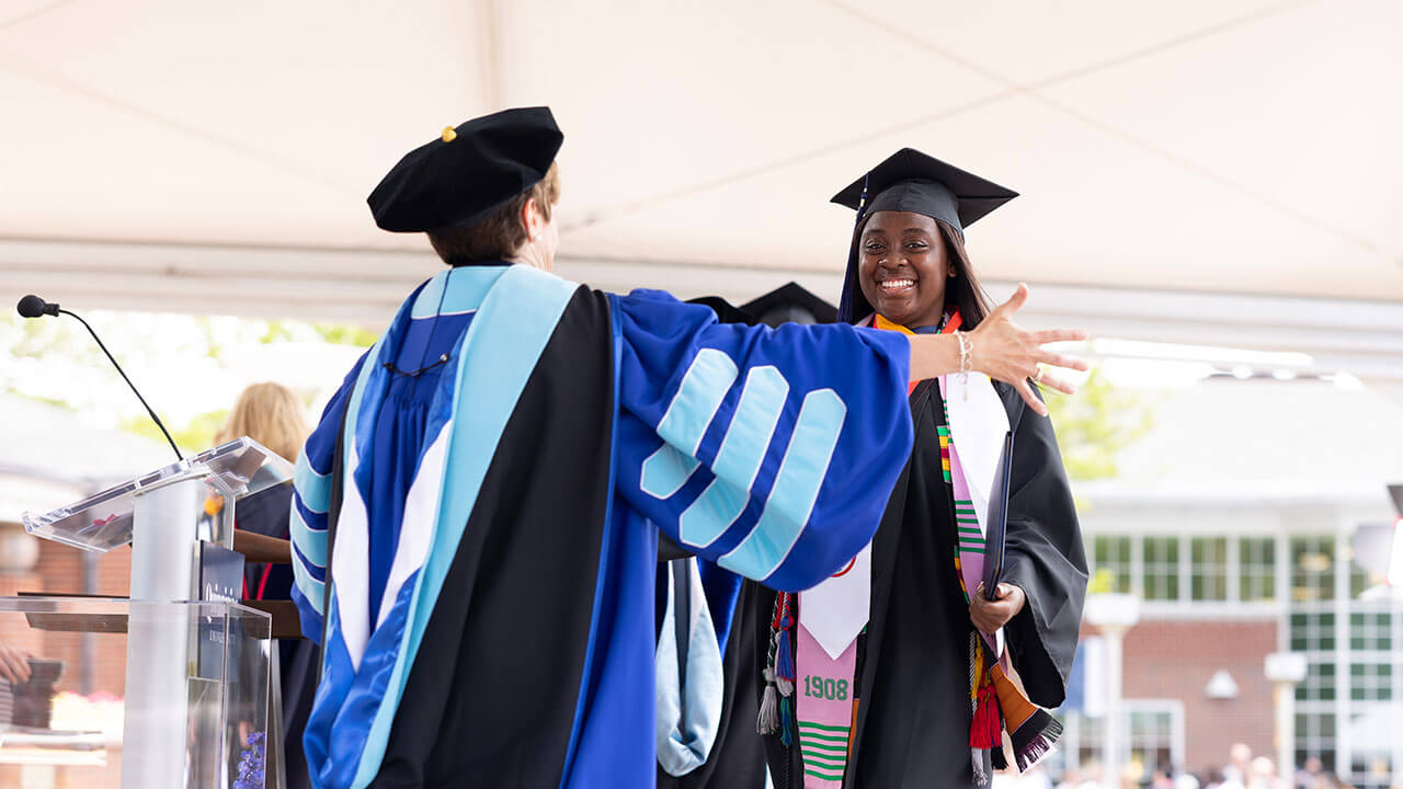 Student going in for a hug with the commencement speaker