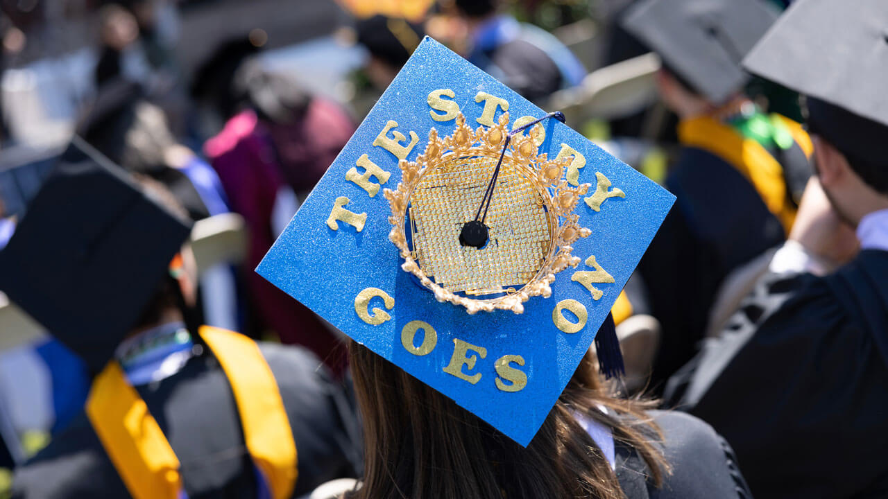 Graduate cap with a crown on top and reads 