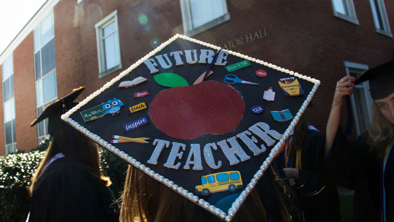 Graduate cap has an apple and says 