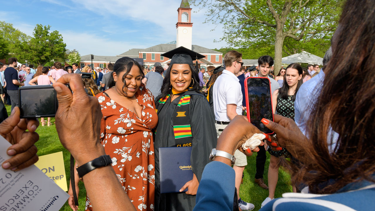 Graduate posing in front of library with friends and family