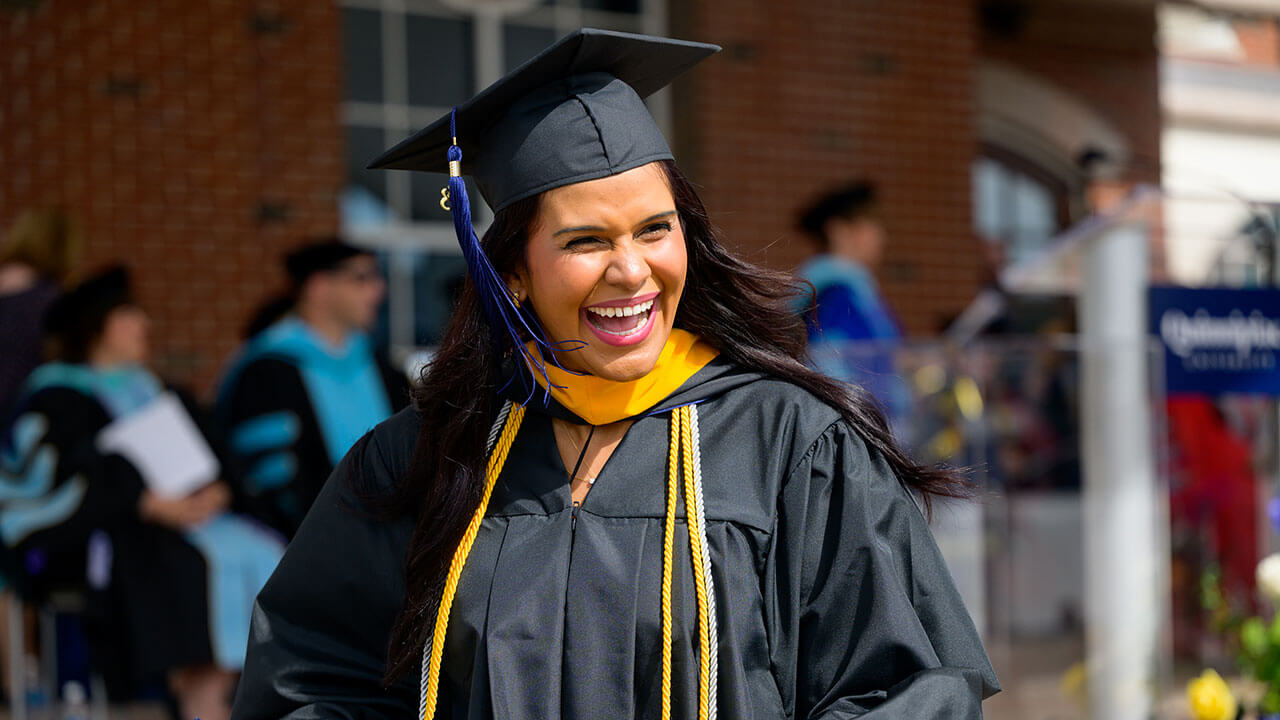 female graduate grins widely while stepping off the stage