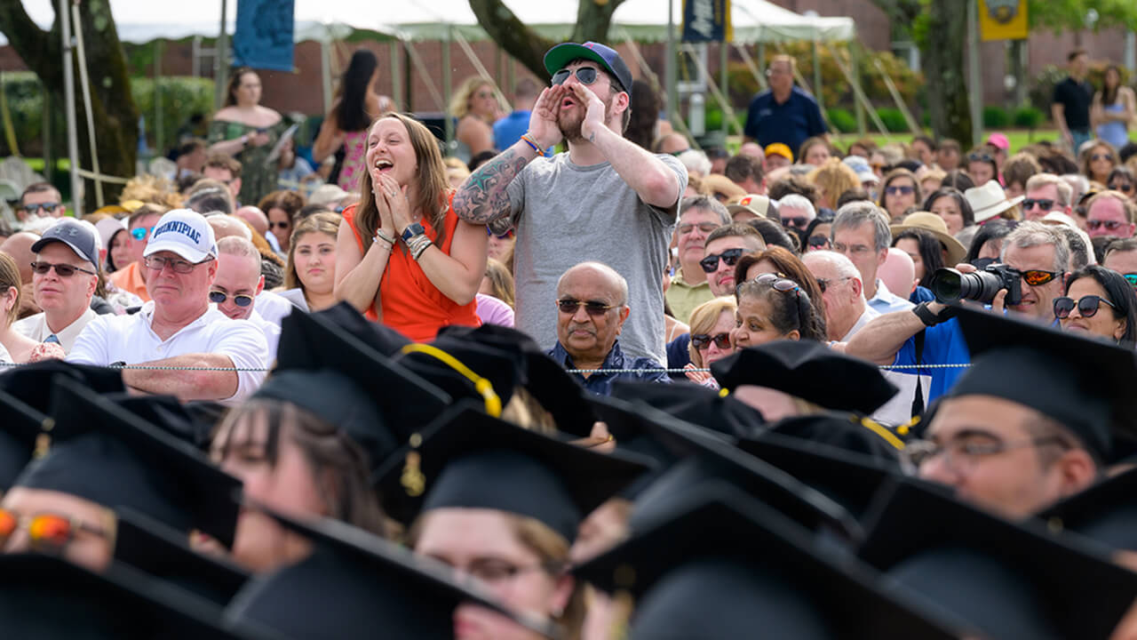 Friends of graduate shout and cheer standing in the crowd