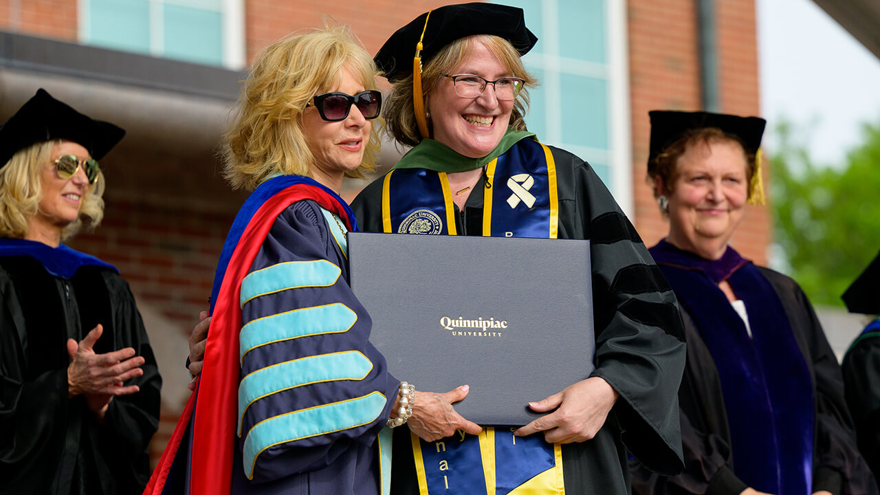 President Olian poses with graduate holding diploma on stage