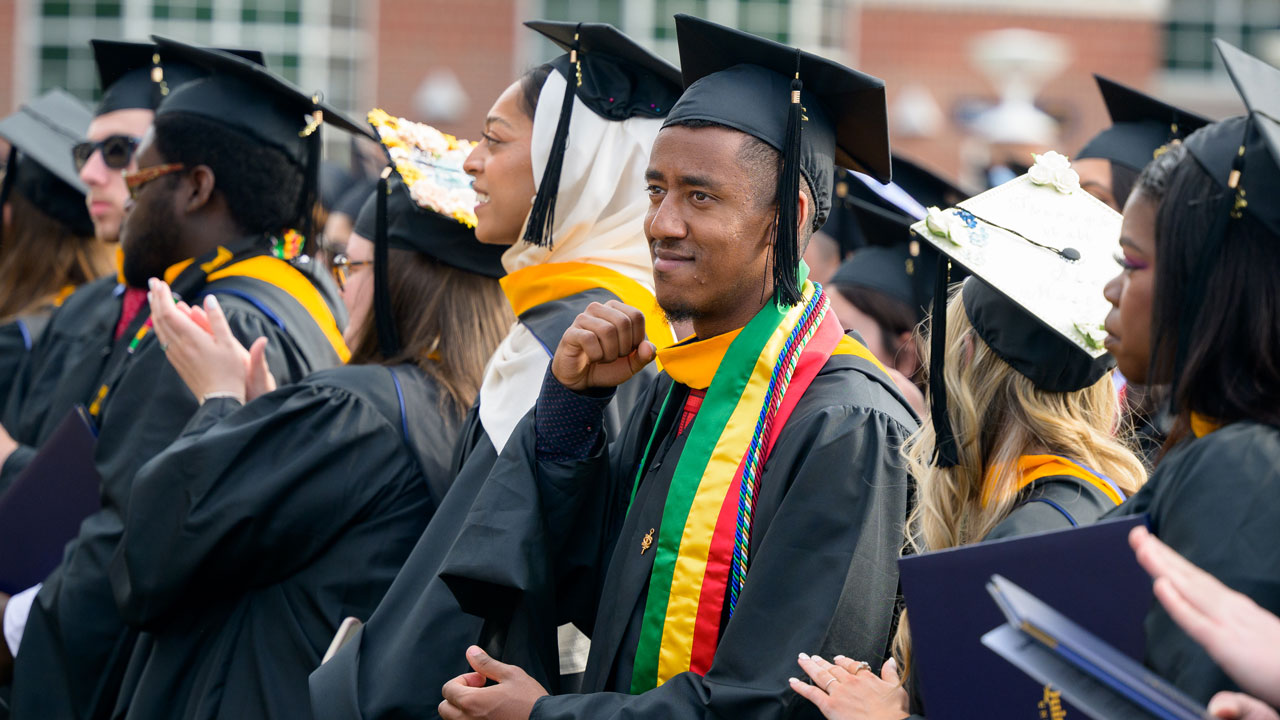 Graduates clapping and standing during commencement