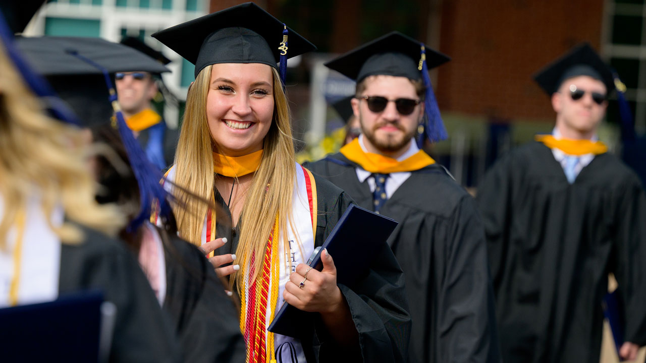 Graduate whole heartedly grinning and walking