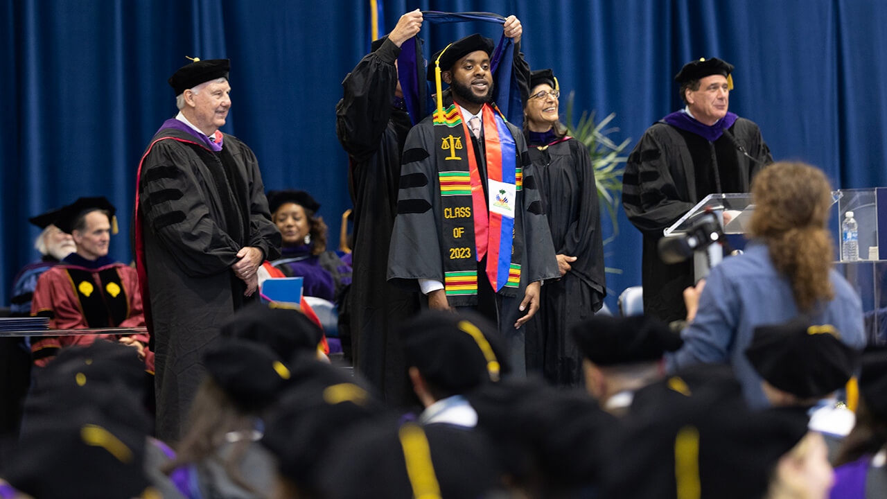 Student looks out to crowd as they receive their hood