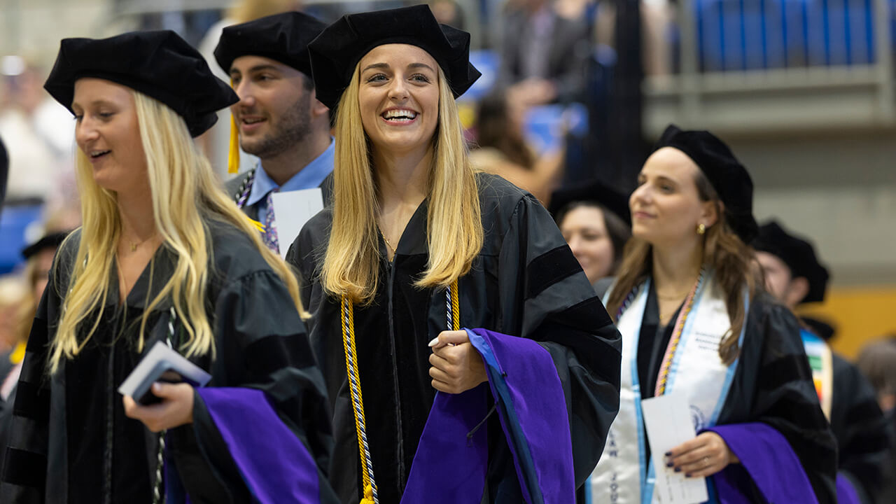 Graduates smile as they walk into the ceremony