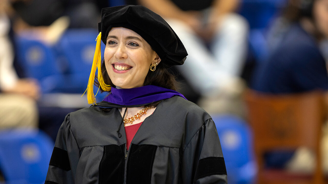 Graduate smiles standing up after receiving their hood