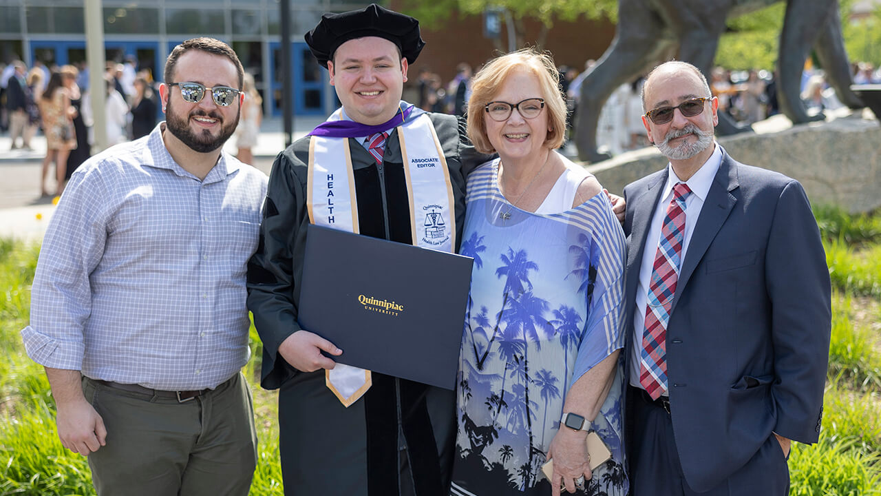 Graduate poses with family in front of bobcat statue