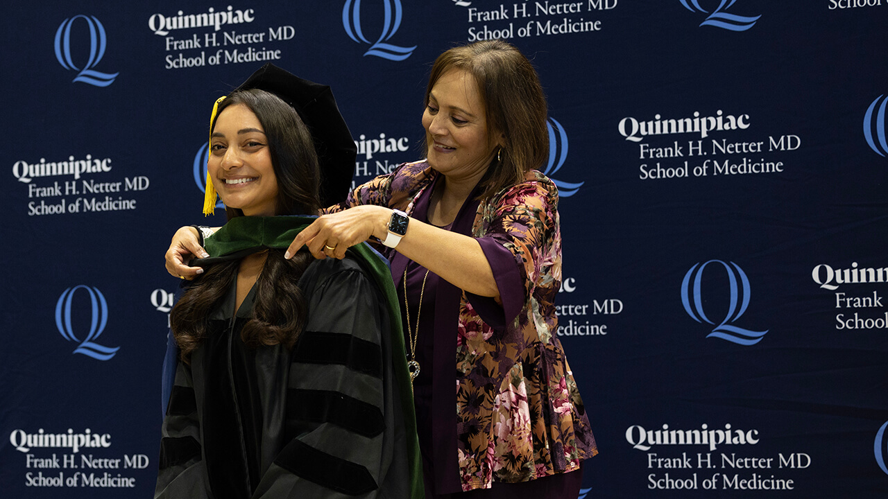 Smiling graduate receives hood