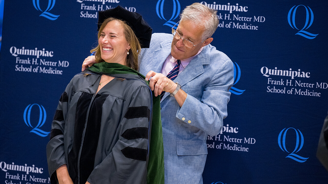 Graduates beam after receiving their hood