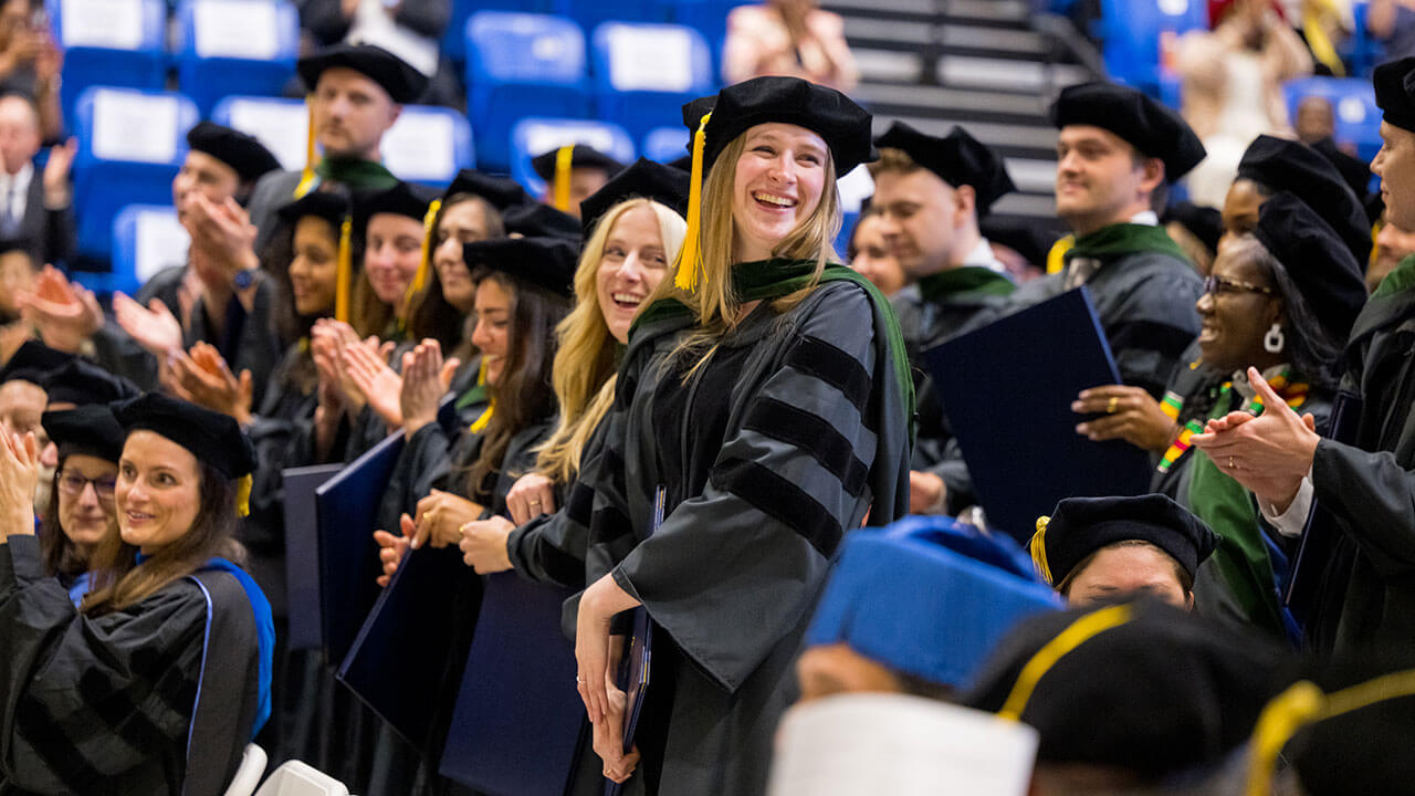 two blonde female graduates smile off camera