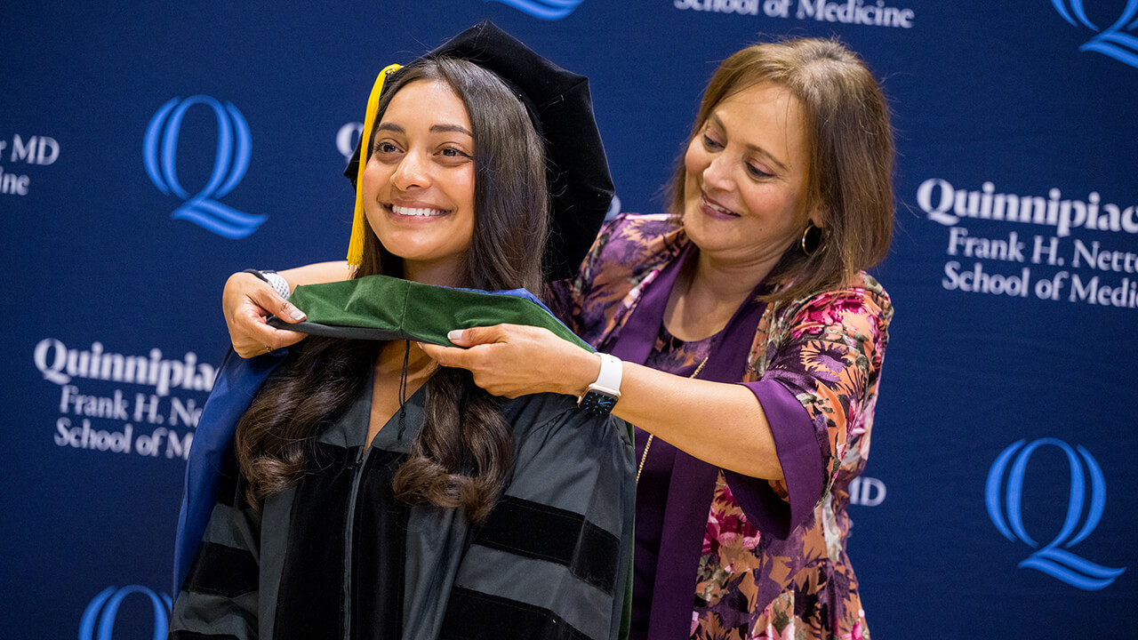 Graduate smiles as family places their hood