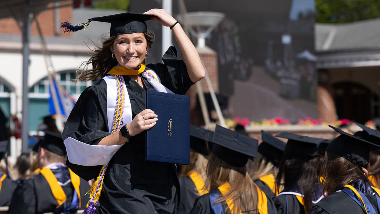 graduate holds onto their cap while they walk down the stairs