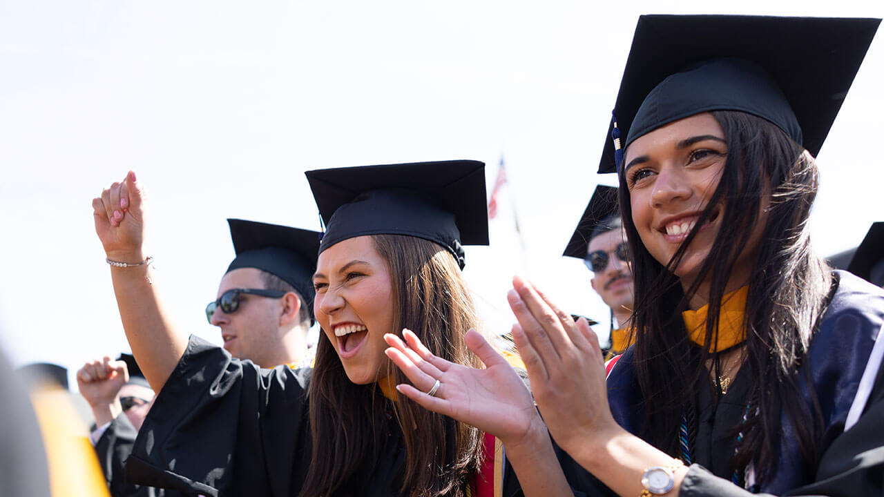 two graduates cheer and clap