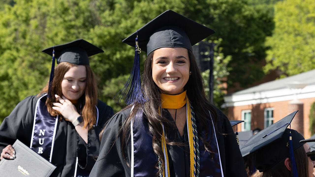 two graduates smile broadly as they head back to their seats