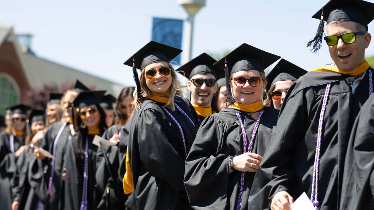 Graduates smile broadly and strike a pose as they line up