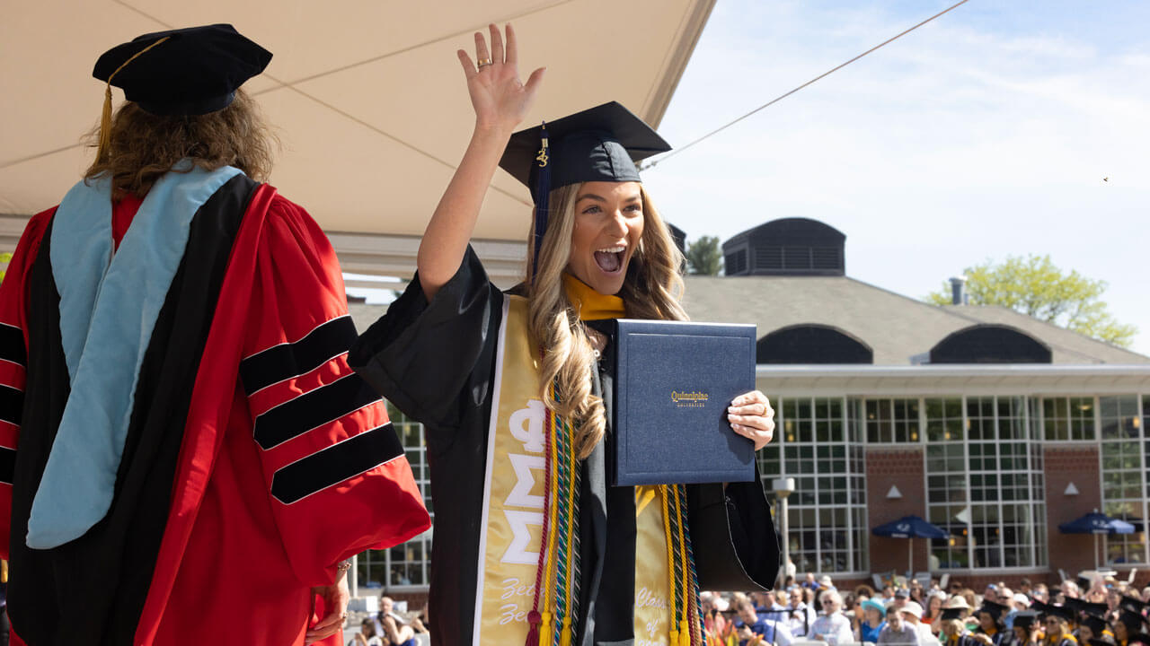 Graduate waving to the crowd and cheering merrily