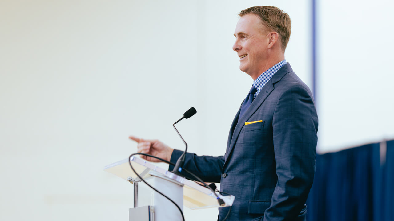 Rand Pecknold speaks from a podium