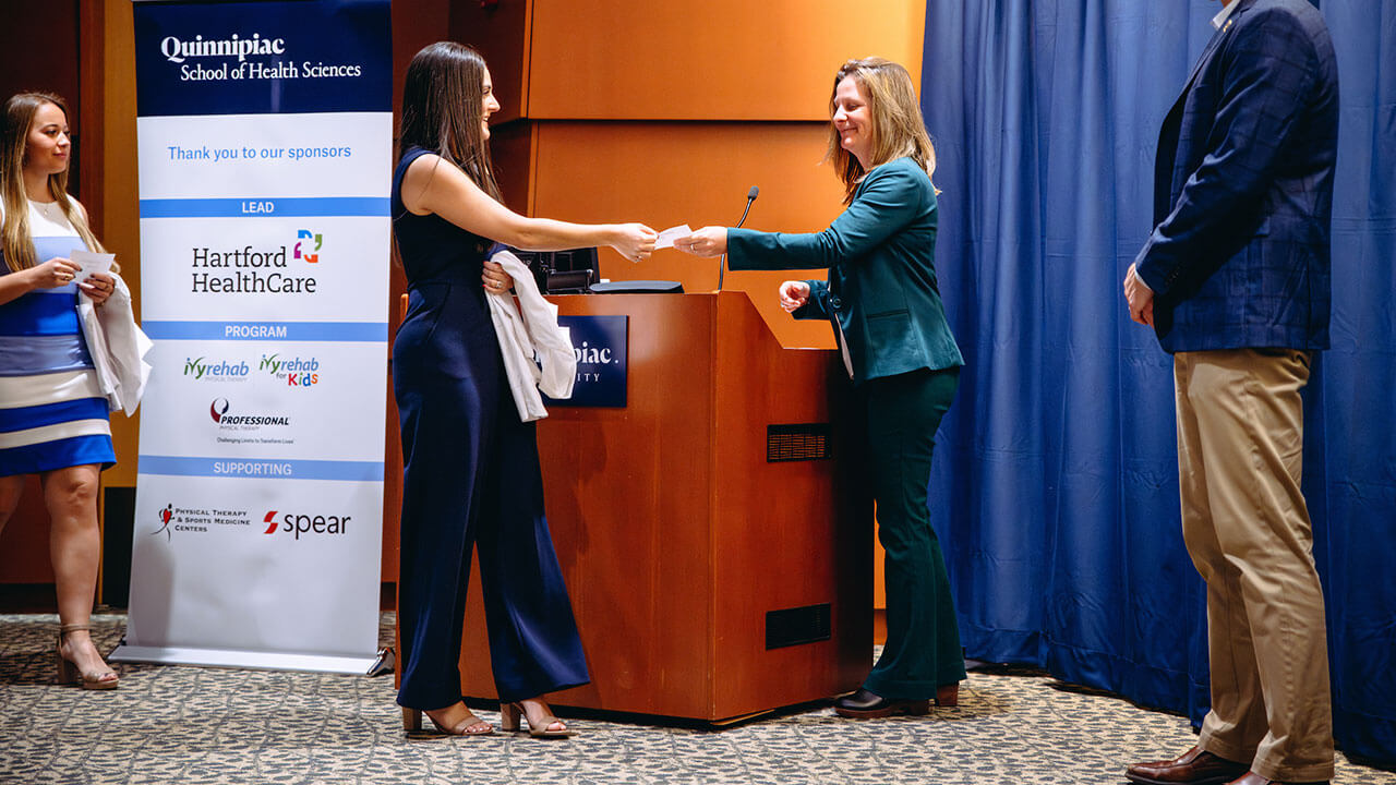 A student shakes hands with a professor at the DPT White Coat ceremony.