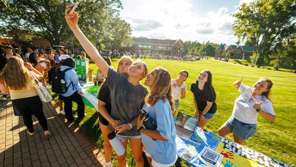 Students taking a selfie in front of Engagement Fair booth