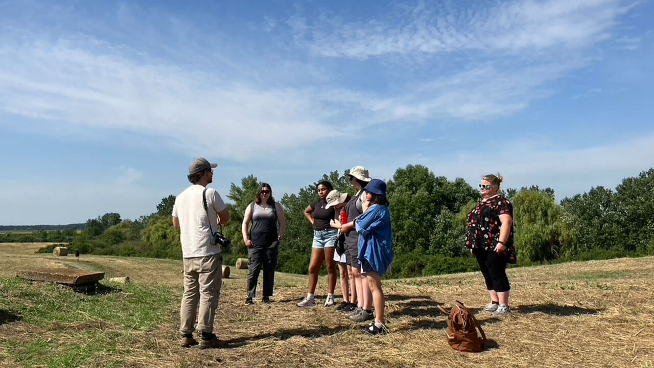 Students standing in a field listening to tour guide