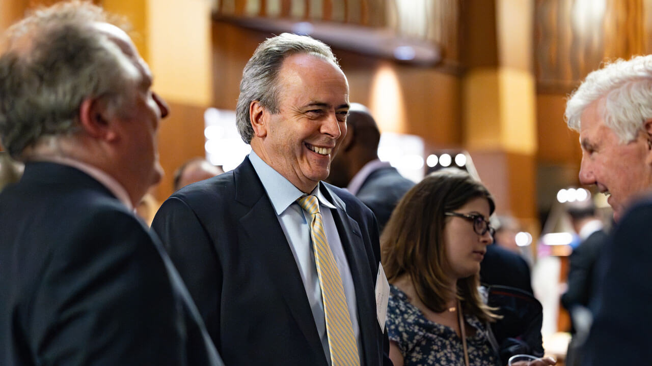 An attendee of the inaugural alumni association awards smiles, wearing a suit and a yellow tie.