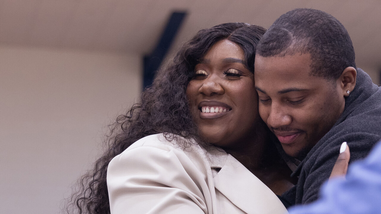 A couple hugging and waiting to open envelope