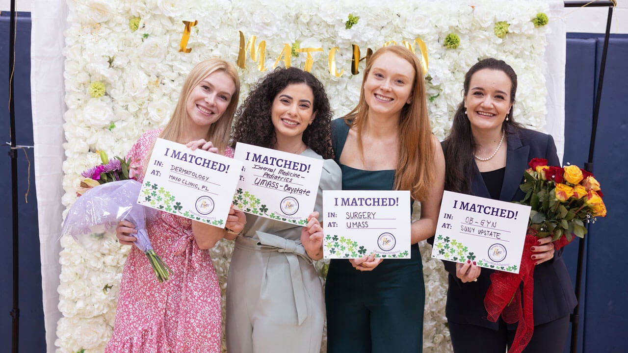 Group of graduate students smiling holding match signs