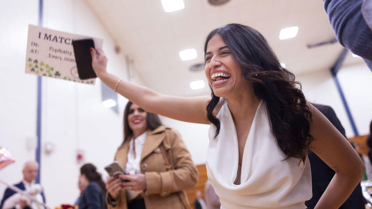 Woman holding her match day paper and cheering