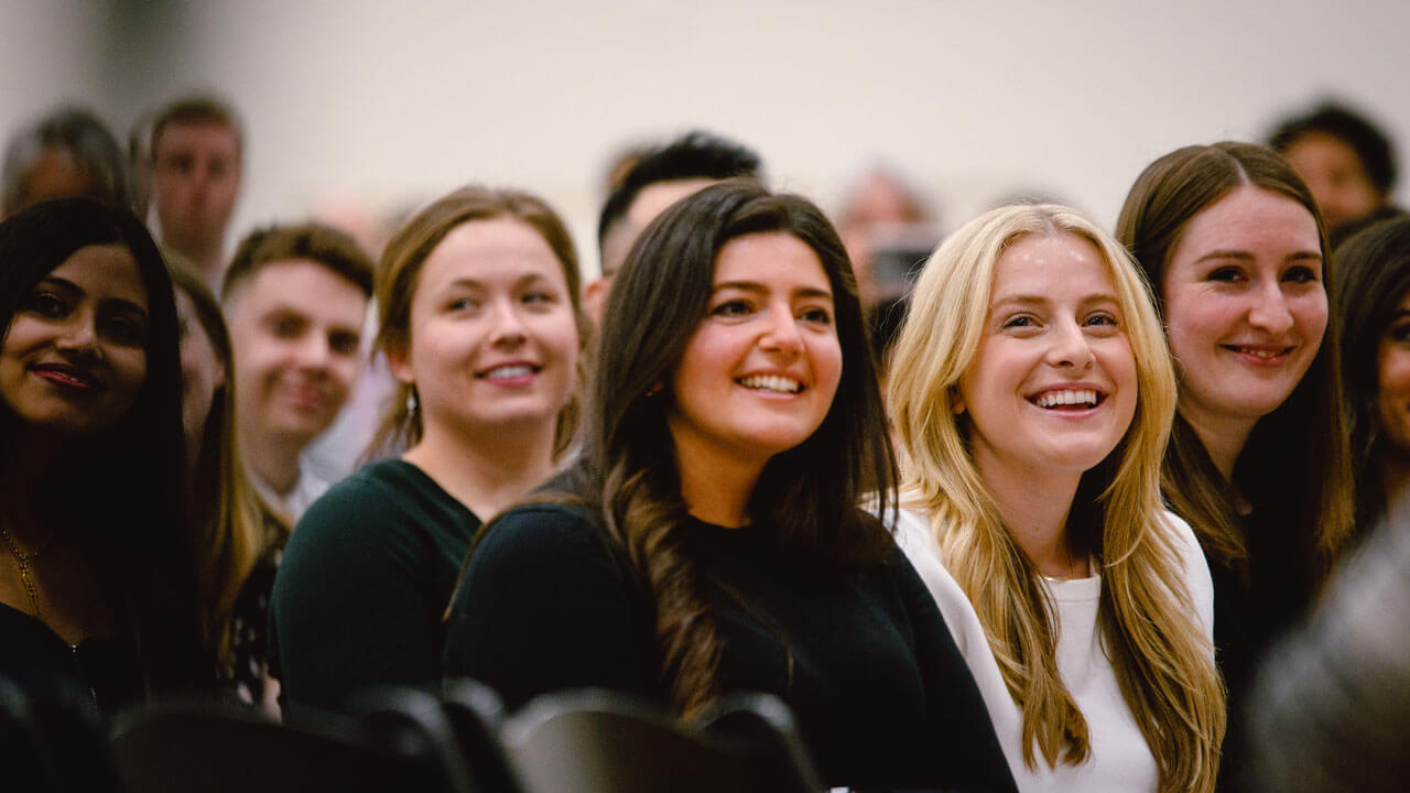 Graduates smiling and watching ceremony