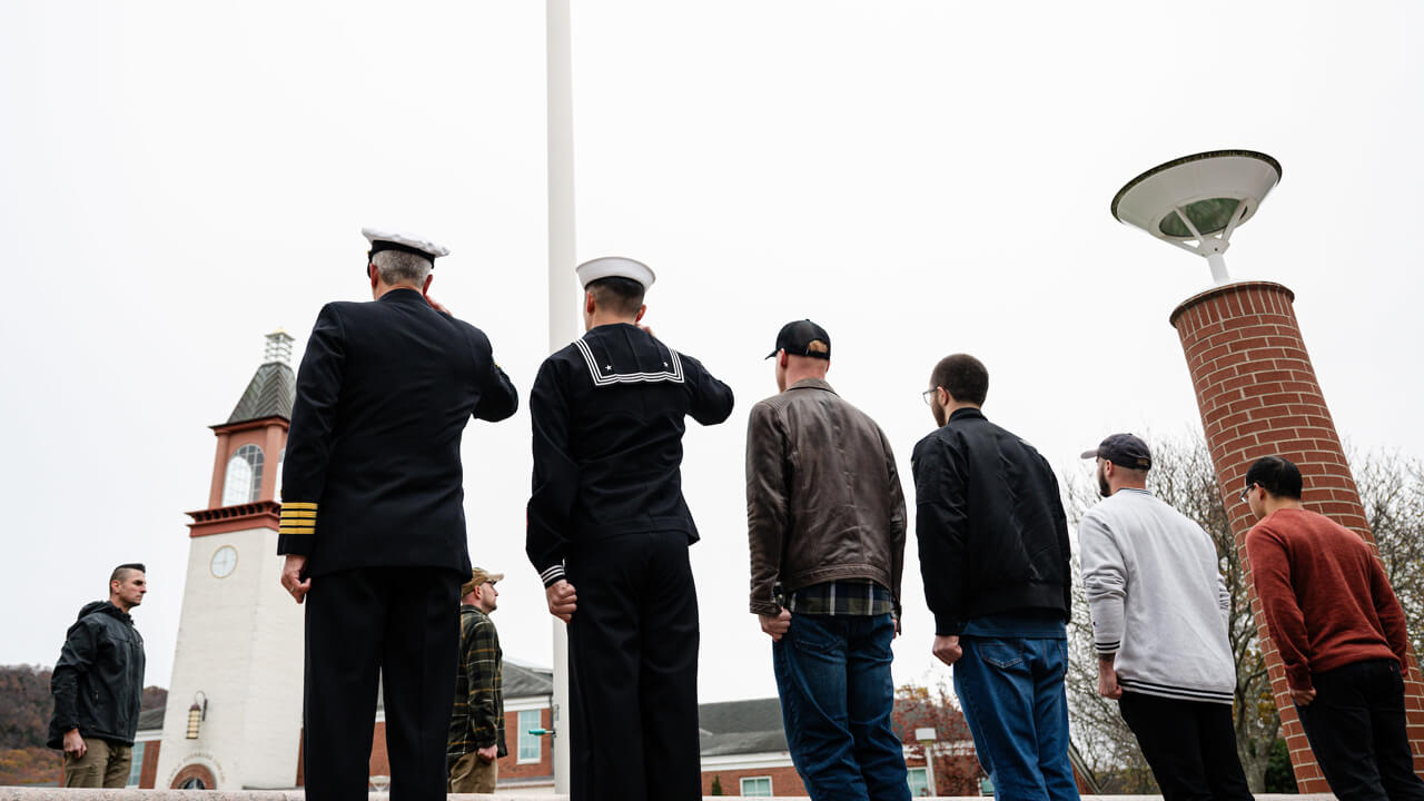 Half a dozen veteran students salute the American flag on the quad