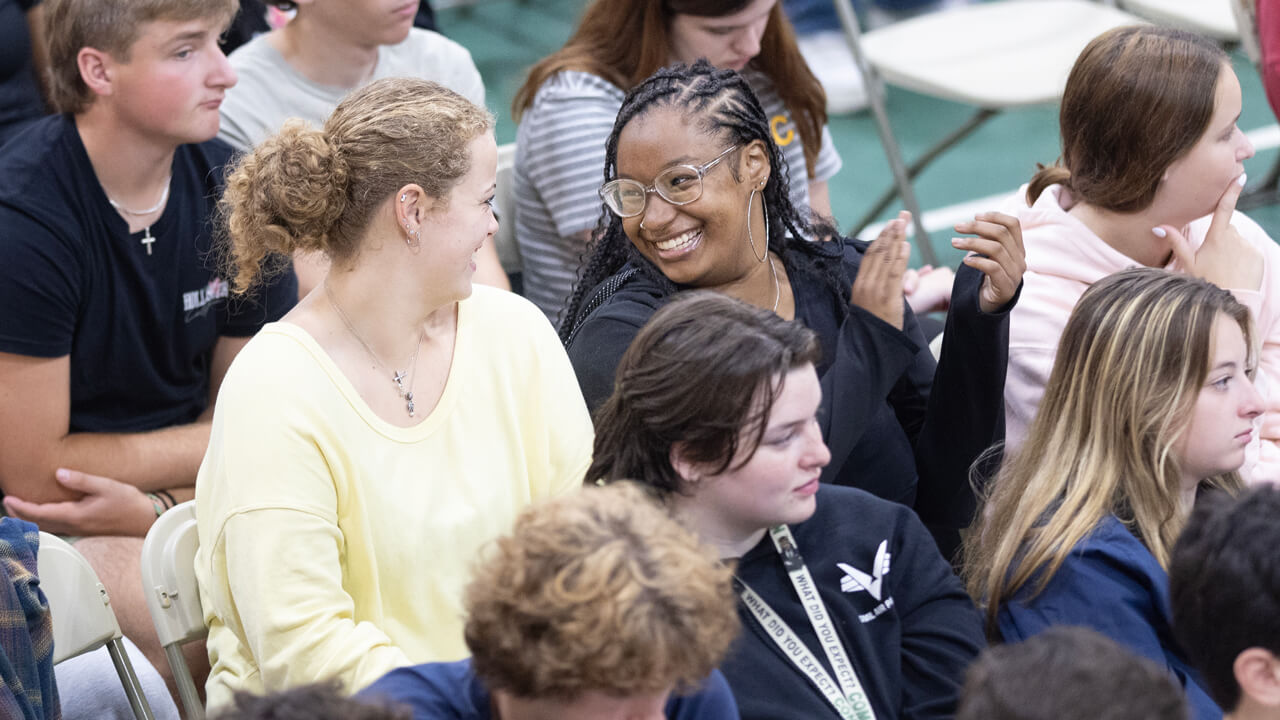 Two students smile at each other and clap during the welcome ceremony