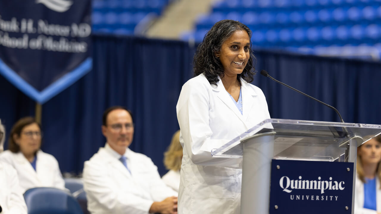 Lyuba Konopasek speaks from the podium on stage during the White Coat Ceremony