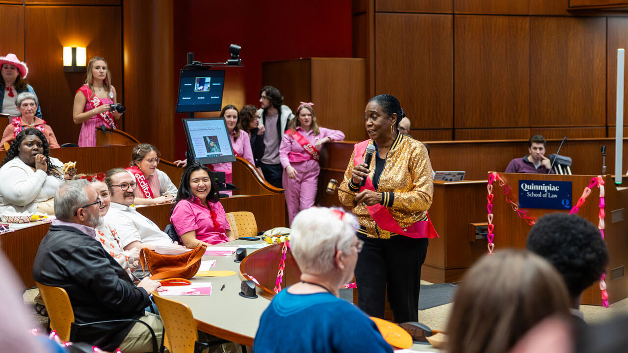 Key note speaker holds micorphone and talks to Quinnipiac Law