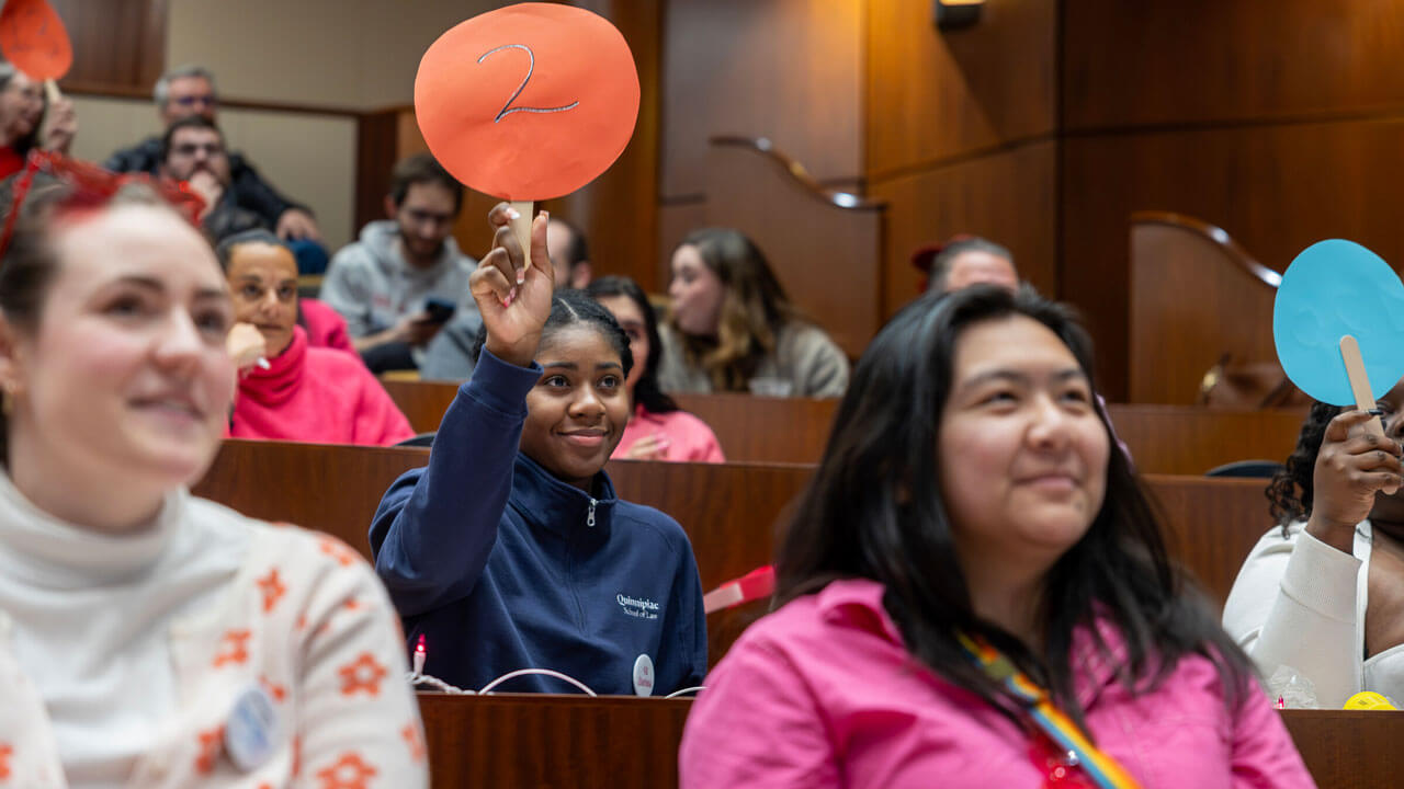 Quinnipiac law student holds up paddle with the number "2"