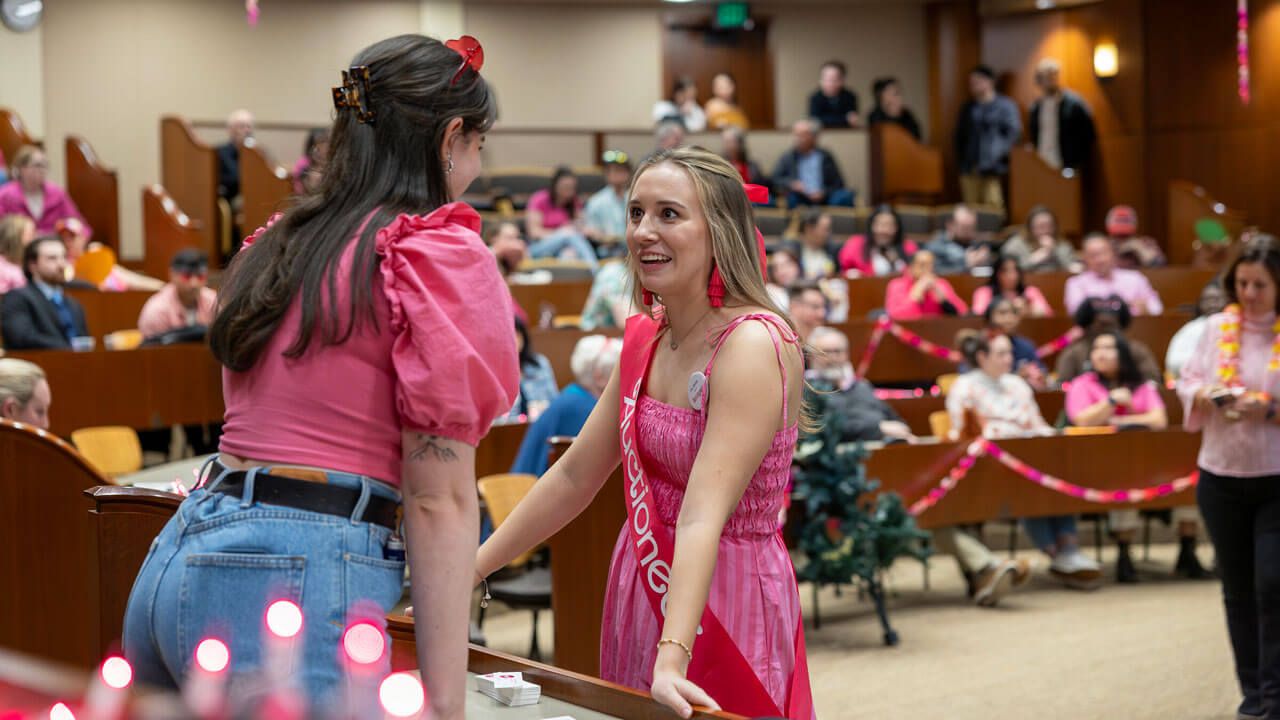 Auctioneer talks to Quinnipiac law student smiling at each other