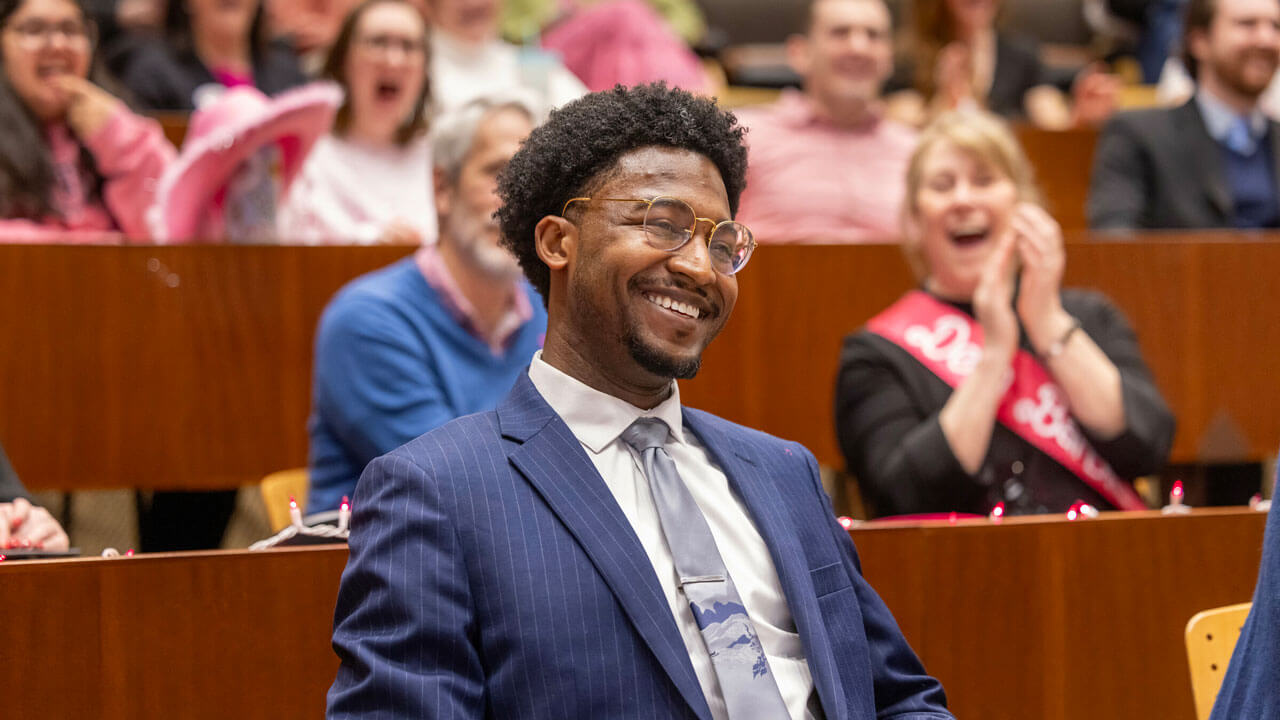 Quinnipiac student smiles as others clap in the audience