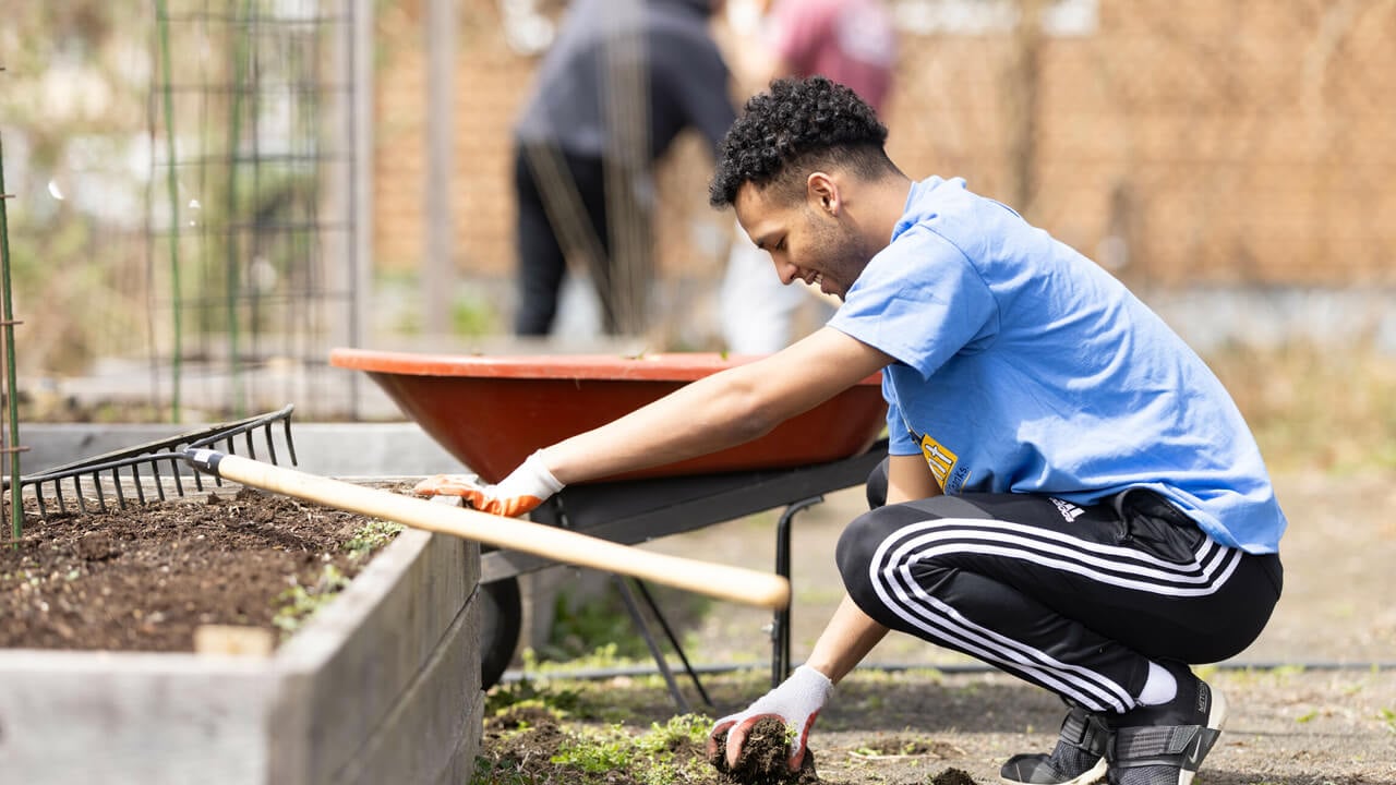 Student picks up dirt from garden