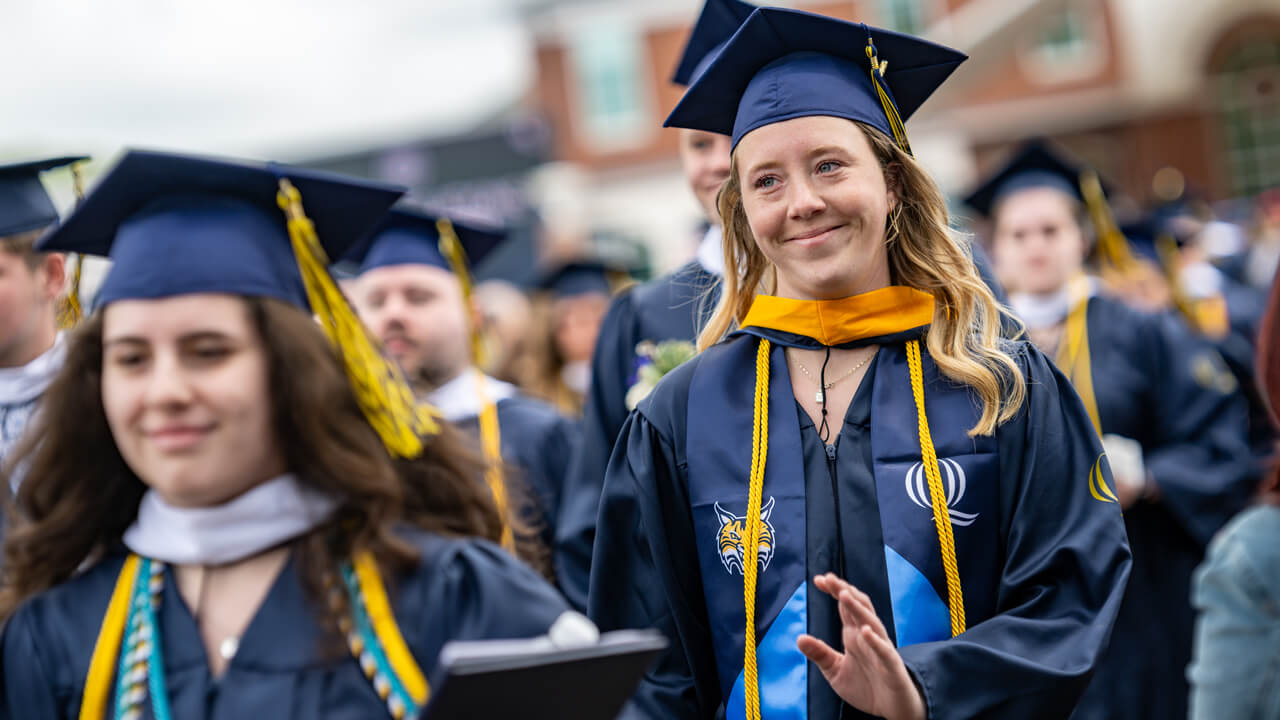 A student athlete smiles and waves to someone in the distance