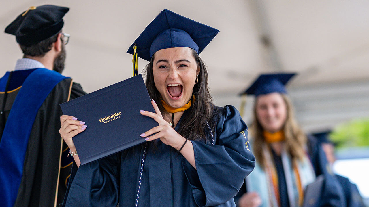 graduate smiles widely with diploma