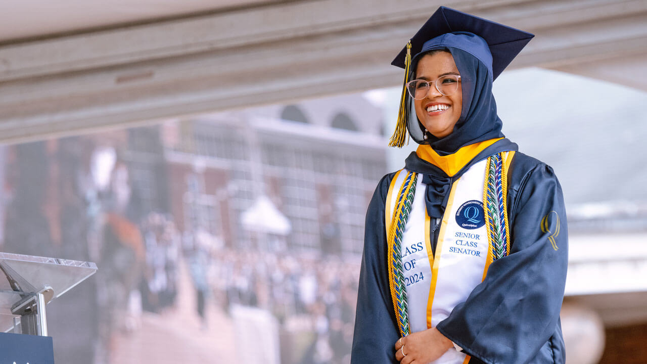 An overjoyed graduate student walks towards center stage to be awarded with their diploma.